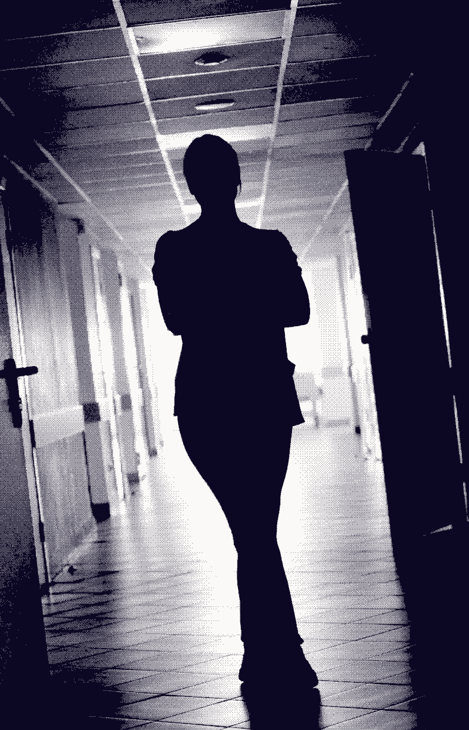 A figure standing with folded arms in a hospital corridor, silhouetted against distant daylight